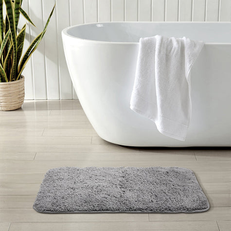 Fluffy light gray bath mat placed in front of the bathtub, enhancing bathroom comfort
