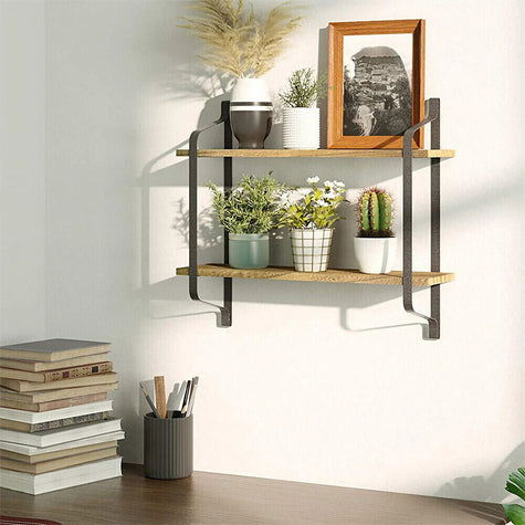 Desk filled with books and a pen holder, industrial-style double wall shelves mounted on the wall holding small potted plants and artwork, creating an artistic vibe