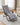Lazy lounge chair positioned in the center of the living room’s gray carpet, with a light gray rectangular cushion tied on, offering comfort and relaxation