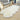 Irregularly shaped white fluffy rug placed on light yellow wood grain flooring, with several sofa chairs nearby, creating a cozy and relaxing space