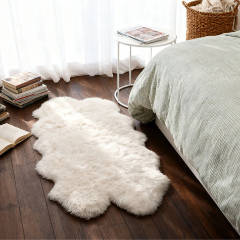 Irregularly shaped white fluffy rug placed on light yellow wood grain flooring, with several sofa chairs nearby, creating a cozy and relaxing space