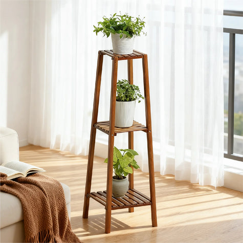 Double-tier plant stand with three supports against a light blue balcony wall, each tier holding a potted plant, surrounded by several smaller pots, creating a fresh and natural vibe
