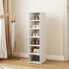 Three columns of stackable white shoe boxes with transparent doors, a person sitting on top demonstrating stability and durability