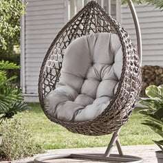 Egg-shaped hanging chair on the balcony with light gray cushion, creating a cozy and relaxing atmosphere