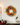 Autumn wreath adorned with maple leaves and small pumpkins hanging on the wall, with decorative items on the table nearby, creating a festive Halloween atmosphere.